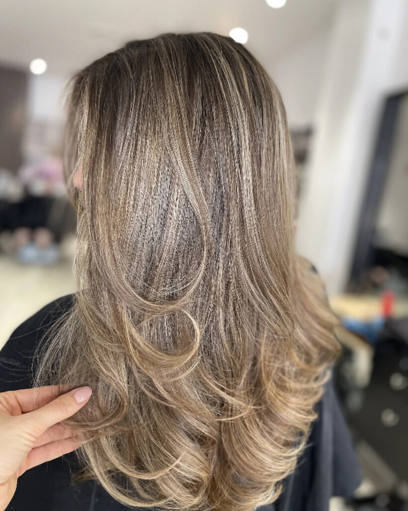 Long layered blonde balayage by Brigitte